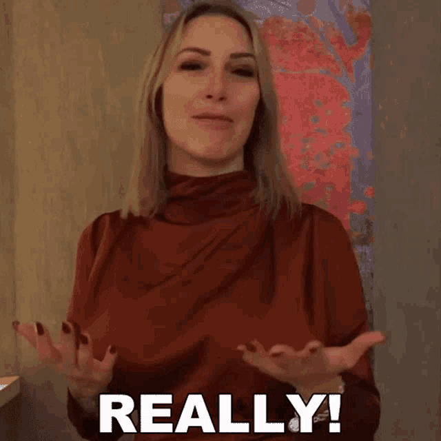a woman in a red top says " really " in front of a painting
