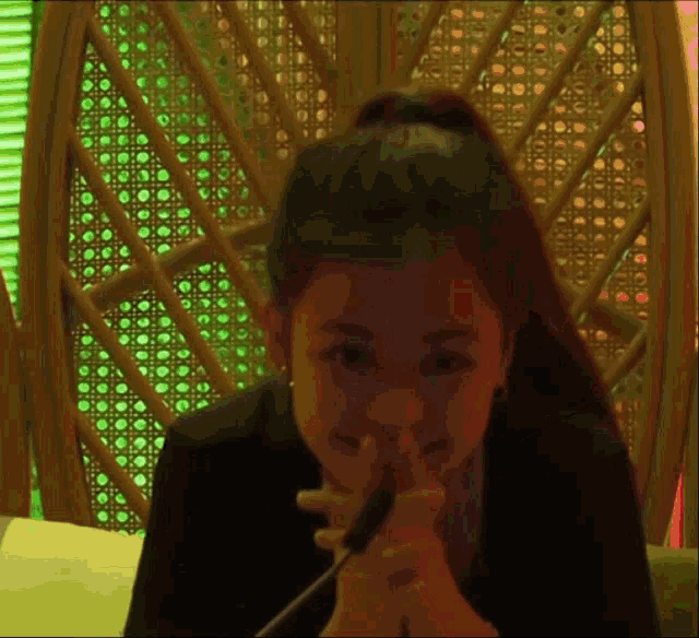 a woman sitting in a chair with her hands folded and a green light behind her
