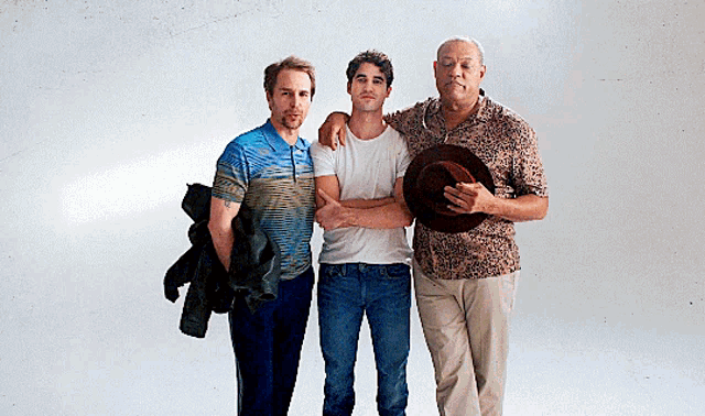 three men are posing for a picture and one of them is holding a hat