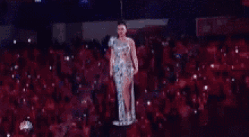 a woman is standing on a platform in front of a crowd .