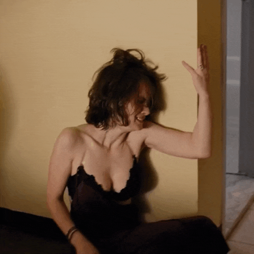 a woman leaning against a wall with her arm up