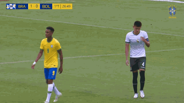 two soccer players on a field with a scoreboard behind them that says bra 1-0 bol
