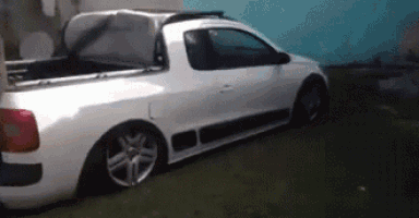 a white truck with the trunk open is parked in a grassy area .