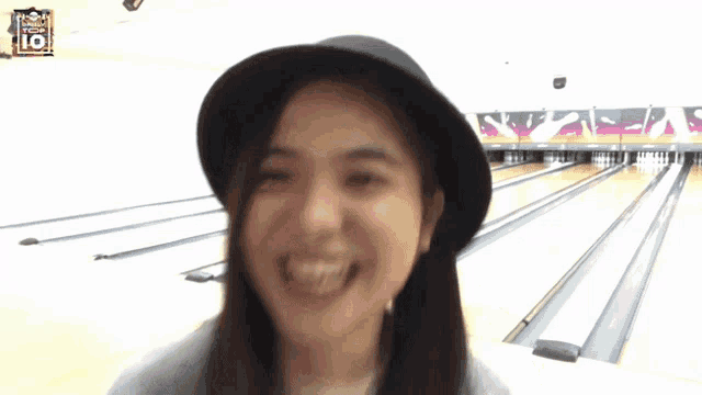 a woman wearing a hat is smiling in front of a bowling alley that says top 10 on it