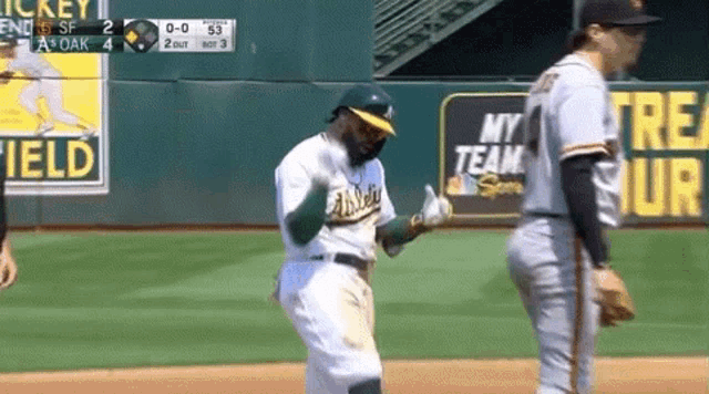 a baseball player wearing an a's jersey is dancing on the field