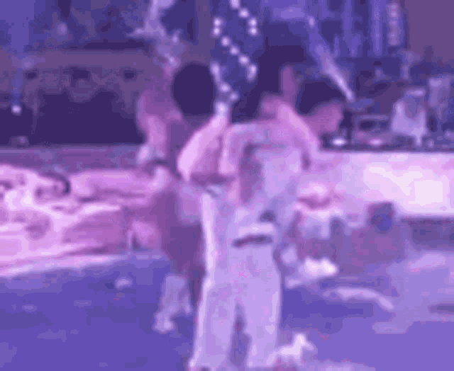 a group of people are dancing on a stage in front of a purple light .