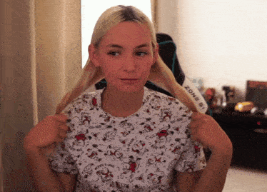 a woman wearing a snoopy shirt holds her hair in front of a zone 51 chair