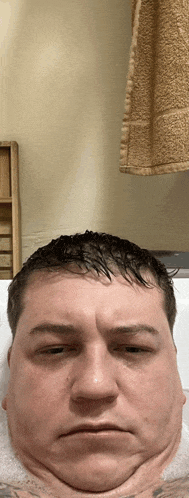 a man in a bathtub with a towel hanging from the wall behind him