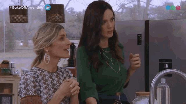 two women are standing in front of a refrigerator with the words bake off argentina above them