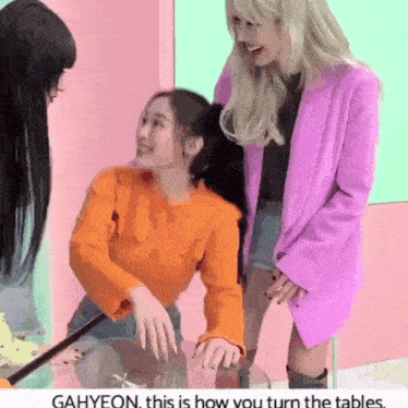 a girl in an orange sweater is sitting at a table with two other girls
