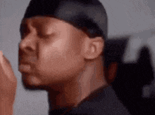 a close up of a man wearing a headband and a black shirt with his eyes closed .