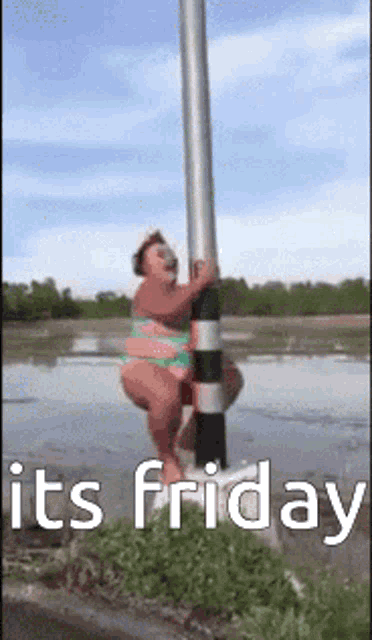 a woman in a bikini is hanging from a pole in the water and says it 's friday .