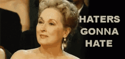 a woman in a white dress is standing in front of a sign that says haters gonna hate