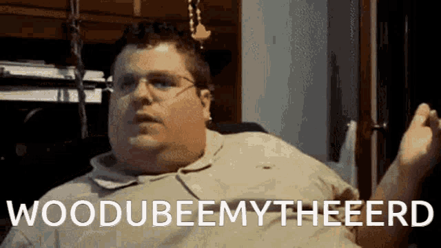 a fat man with glasses is sitting in a chair and says woodubeemy theeerd