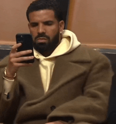 a man in a tan coat is holding a cell phone