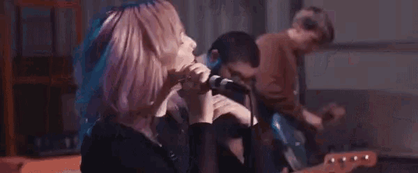 a woman is singing into a microphone while a man plays a guitar .