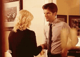 a man and a woman are shaking hands in a living room .