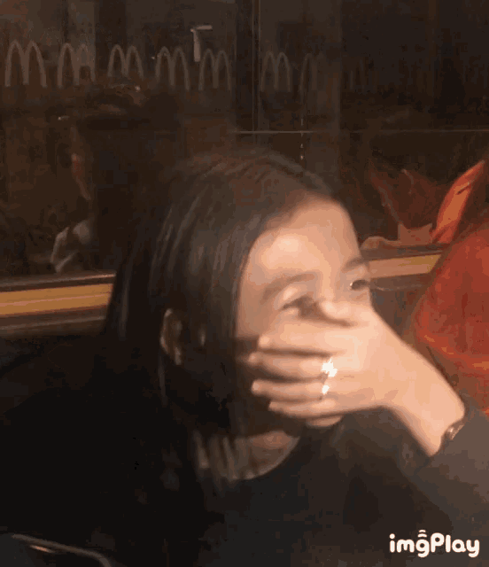 a woman covering her face in front of a mcdonald 's window