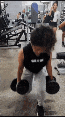 a person lifting dumbbells in a gym with a black tank top that says ' ur fi on ' on it