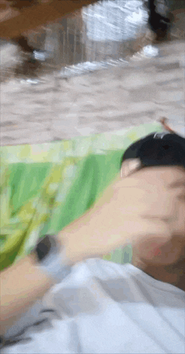 a man wearing a hat and a watch is laying on a green blanket .