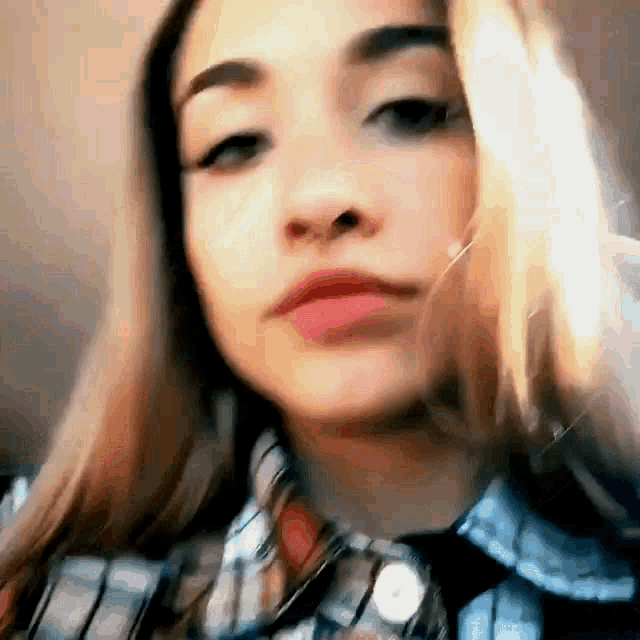 a close up of a woman 's face wearing a plaid shirt