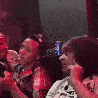 a group of people are sitting in a dark room with a can of pepsi on the table .