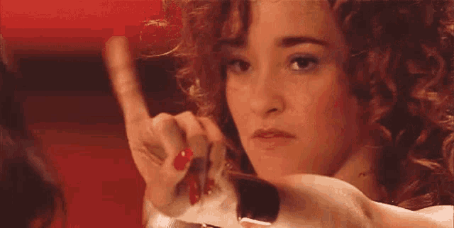 a woman with curly hair is looking at herself in a mirror .