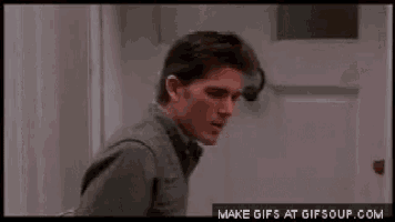 a man in a sweater is standing in front of a door and looking at something .