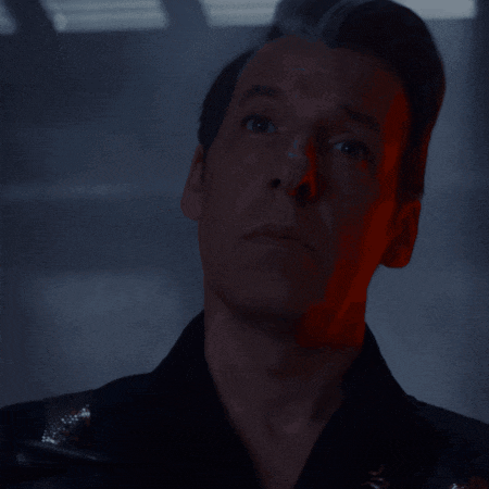a close up of a man 's face with red light behind him