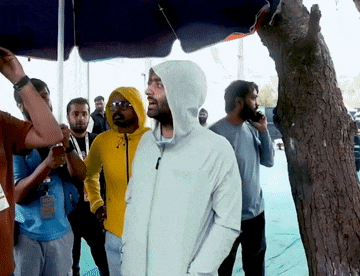 a man wearing a hooded jacket with the word north face on it stands in a crowd of people
