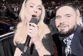 a woman singing into a microphone next to a man in a suit