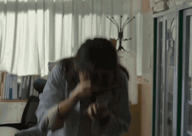 a woman in a white shirt is covering her face with her hands in an office .
