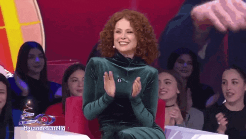 a woman in a green dress applauds in front of a crowd of people
