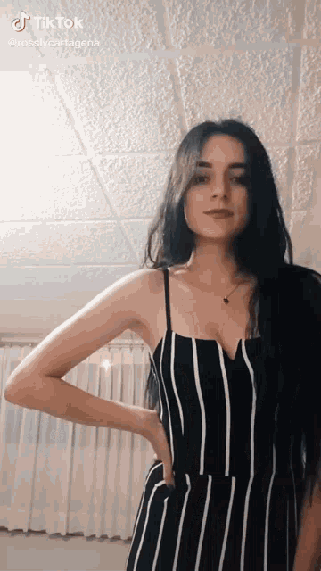 a woman in a black and white striped dress is standing in front of a white curtain