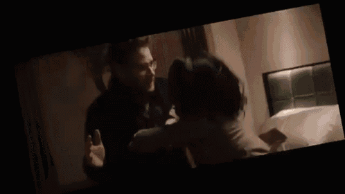 a man and a woman are standing next to each other in a dark room and looking at each other .