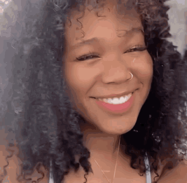 a woman with curly hair is smiling for the camera