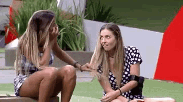 two women are sitting next to each other on a couch and talking to each other .