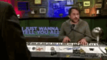 a man is singing into a microphone while playing a keyboard