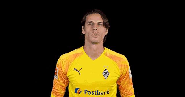 a man wearing a yellow postbank jersey is smiling