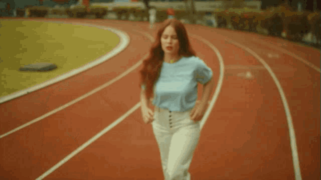 a woman running on a track wearing a blue t-shirt