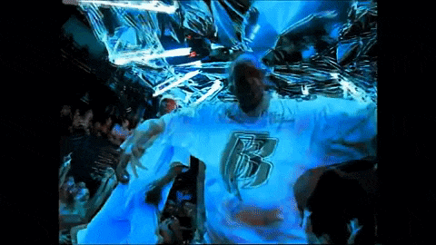 a man wearing a shirt with the letter b on it stands in front of a crowd