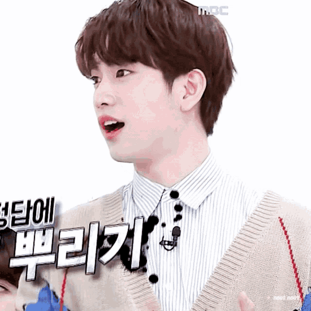 a young man wearing a striped shirt and a sweater with korean writing on it .