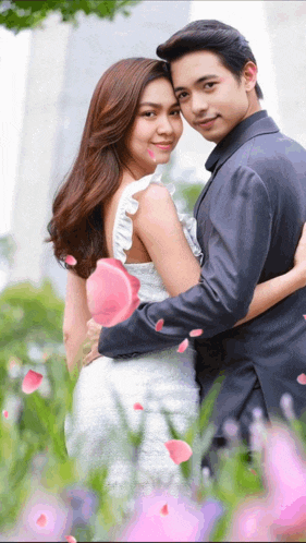 a man in a suit and a woman in a white dress hugging