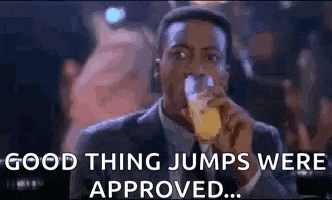 a man in a suit is drinking a glass of beer and saying `` good thing jumps were approved . ''