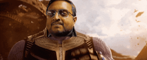 a man with glasses and a beard is standing in front of a mountain .