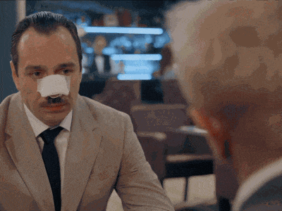 a man with a bandage on his nose is talking to another man