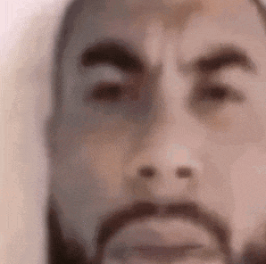 a close up of a man 's face with a beard and a serious look on his face .