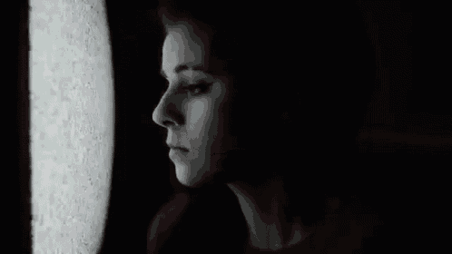 a woman in a red shirt is looking out of a window .