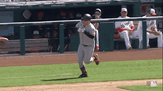 a baseball player is running towards home plate while the dugout watches .