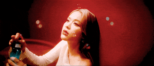 a woman in a white sweater is blowing soap bubbles against a red background